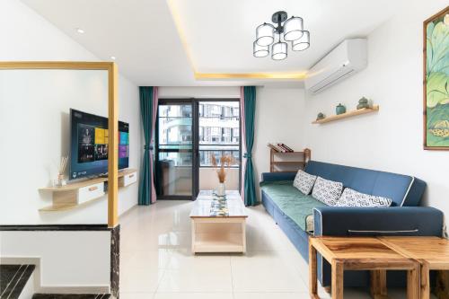 a living room with a blue couch and a tv at Poly Central Plaza By Boli at Sanya City Center#Near Joy City in Sanya