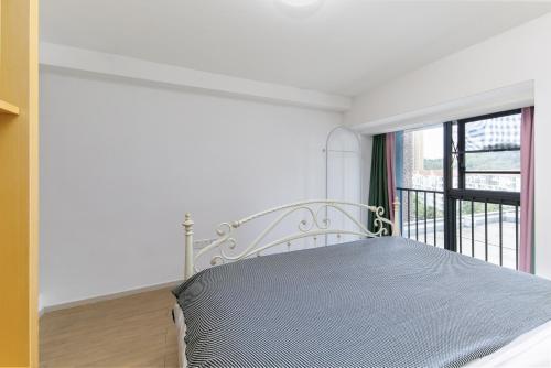 a white bed in a room with a window at Poly Central Plaza By Boli at Sanya City Center#Near Joy City in Sanya