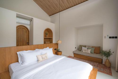 a bedroom with a large white bed and a couch at The Cendana Villa Yogyakarta in Bedoyo