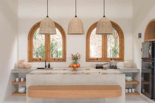 a kitchen with two arched windows and a large kitchen island at The Cendana Villa Yogyakarta in Bedoyo