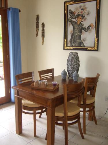a dining room table with chairs and a picture on the wall at Guesthouse Rumah Senang in Kalibaru