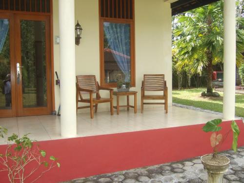 a porch of a house with chairs and a table at Guesthouse Rumah Senang in Kalibaru