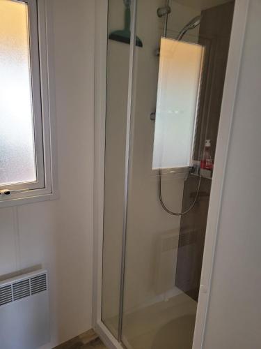 La salle de bains est pourvue d'une douche en verre et d'une fenêtre. dans l'établissement Vue bassin Arcachon mobil-home top 8 personnes by Vayny, à Lège-Cap-Ferret