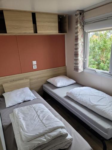deux lits dans une chambre avec une fenêtre dans l'établissement Vue bassin Arcachon mobil-home top 8 personnes by Vayny, à Lège-Cap-Ferret
