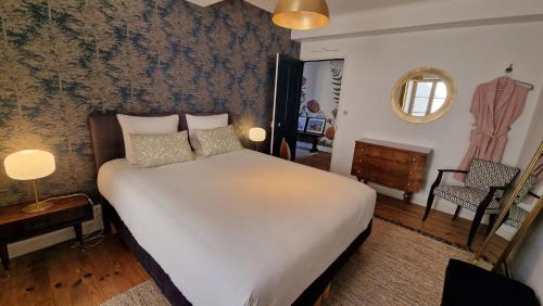 a bedroom with a large white bed and a chair at La maison du Mont Saint Michel in Pontorson