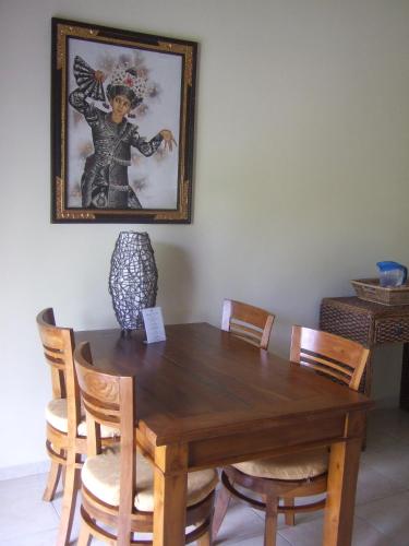 a wooden table with chairs and a picture on the wall at Guesthouse Rumah Senang in Kalibaru