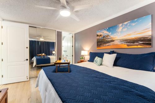 a bedroom with a large bed with a blue blanket at Beautiful Oceanview, Great Location Across the Beach in Wailea