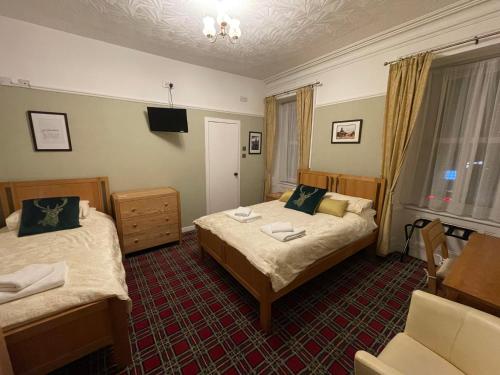 a hotel room with two beds and a chair at Stag and Barrel in Elgin
