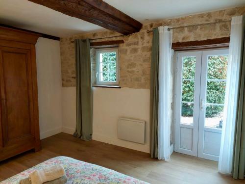 a bedroom with a bed and two windows and a door at Les chambres d'Omaha Beach Etablissement avec deux chambres d'hôtes, petit-déjeuner compris fait-maison et produits locaux in Vierville-sur-Mer
