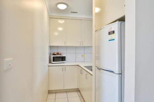 a kitchen with white cabinets and a refrigerator at Cottonwood Motor Inn in Mildura