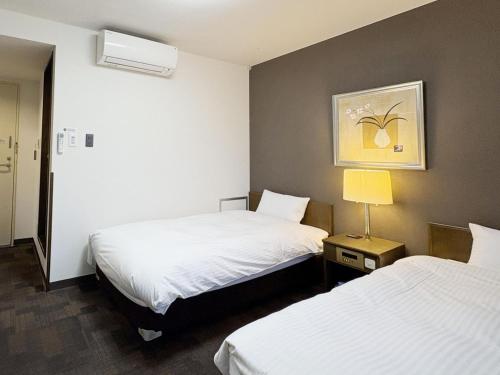 a hotel room with two beds and a lamp at Hotel Route-Inn Court Uenohara in Uenohara