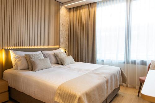 a bedroom with a large white bed with a window at Hôtel des Innovations in Marly-le-Grand