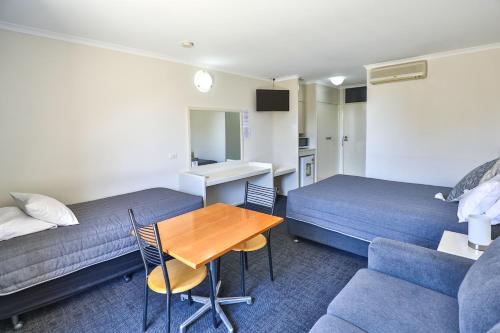 a hotel room with two beds and a table and a couch at Cottonwood Motor Inn in Mildura