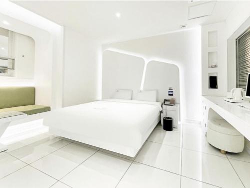 a white bedroom with a bed and a sink at Zara Hotel Peace Square in Mokpo