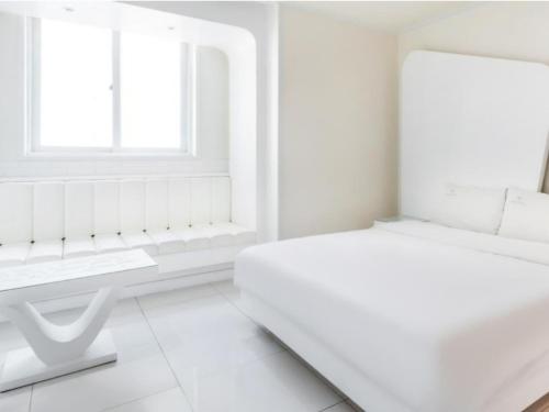 a white room with a bed and a window at Zara Hotel Peace Square in Mokpo
