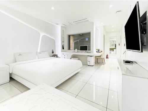 a white room with a white bed and a desk at Zara Hotel Peace Square in Mokpo