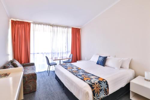 a hotel room with a large bed and a table at Cottonwood Motor Inn in Mildura