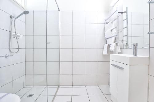 a white bathroom with a shower and a sink at Cottonwood Motor Inn in Mildura