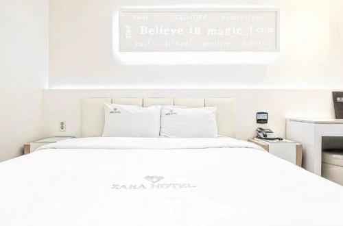 a bedroom with a white bed with a sign above it at Zara Hotel Peace Square in Mokpo
