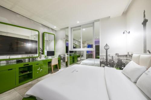 a bedroom with a large white bed and a tv at Zara Hotel Peace Square in Mokpo