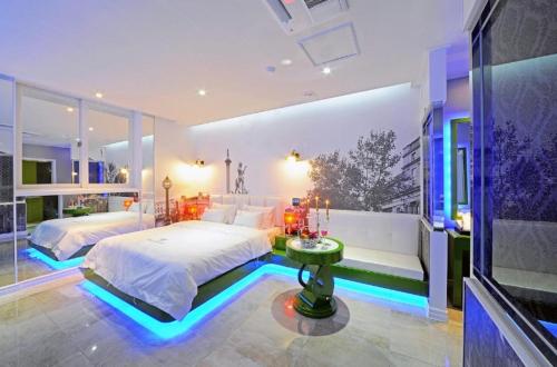 a bedroom with two beds and a table in it at Zara Hotel Peace Square in Mokpo