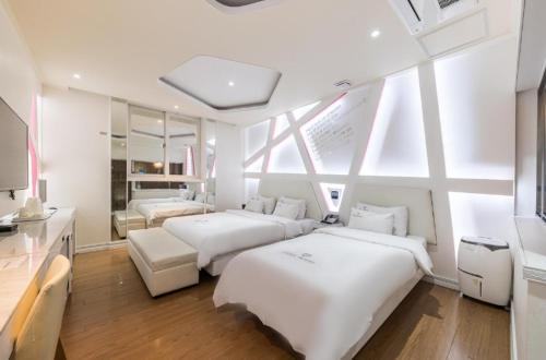 a bedroom with two beds and a large window at Zara Hotel Peace Square in Mokpo