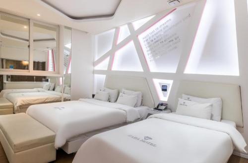 a room with three beds and a window at Zara Hotel Peace Square in Mokpo