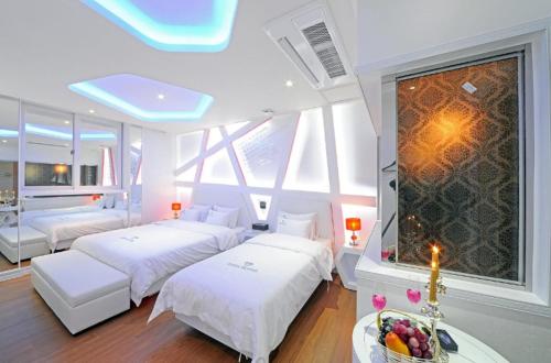 a bedroom with two beds and a large window at Zara Hotel Peace Square in Mokpo