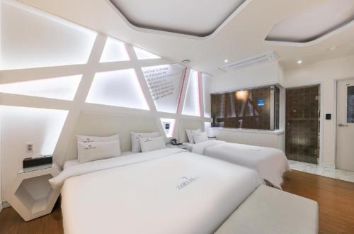a bedroom with two white beds and a large window at Zara Hotel Peace Square in Mokpo