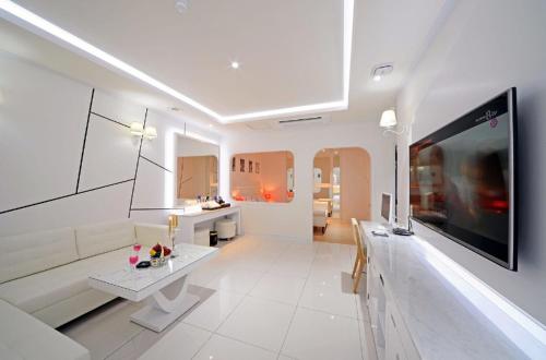 a large white living room with a tv on a wall at Zara Hotel Peace Square in Mokpo