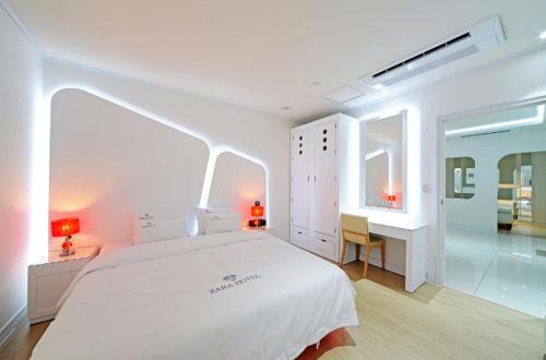 a white bedroom with a large bed and a desk at Zara Hotel Peace Square in Mokpo