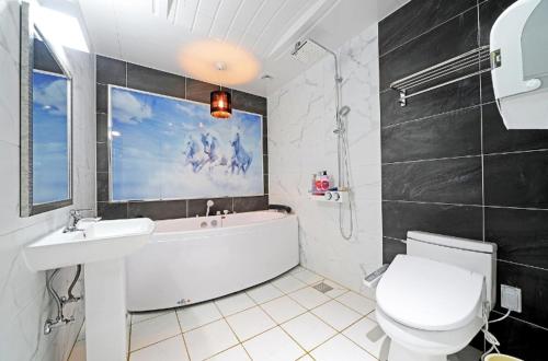 a bathroom with a tub and a sink and a toilet at Zara Hotel Peace Square in Mokpo