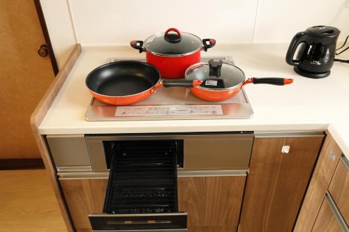 two pots and pans sitting on top of a stove at つるのやど 