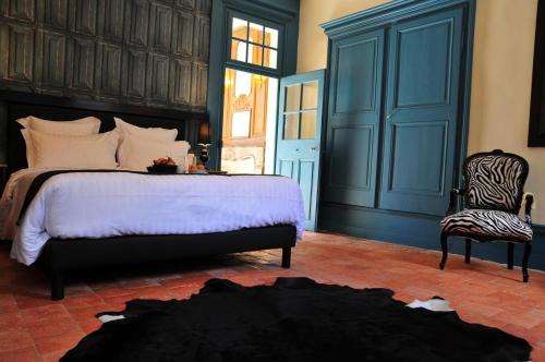 a bedroom with a large bed and a chair at Les Glycines Vézelay in Vézelay