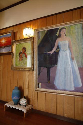 a painting of a woman playing a piano on a wall at つるのやど 