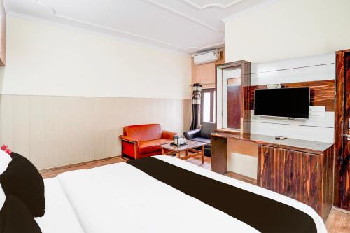 a hotel room with a bed and a flat screen tv at Super Hotel O Tyagi Road near Railway Station in Dehradun