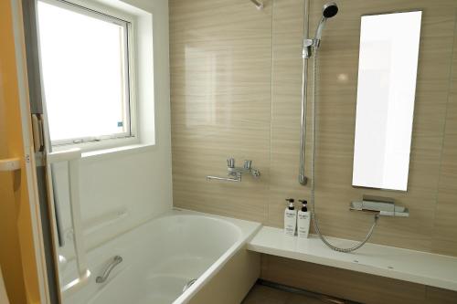 a bathroom with a tub and a shower with a window at つるのやど 