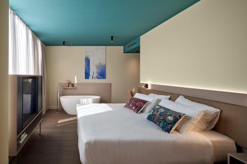 a bedroom with a bed and a tub and a television at WANDERLUST HOTEL - SUITE & SPA - APARTMENTS & VILLAS - Bardolino, Lago di Garda - Verona in Bardolino