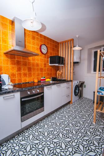 a kitchen with orange tiled walls and white cabinets at Fortaleza do Pico Apartment in Funchal