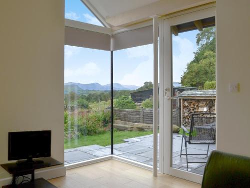 a living room with a sliding glass door with a television at Cottam Road in Threlkeld
