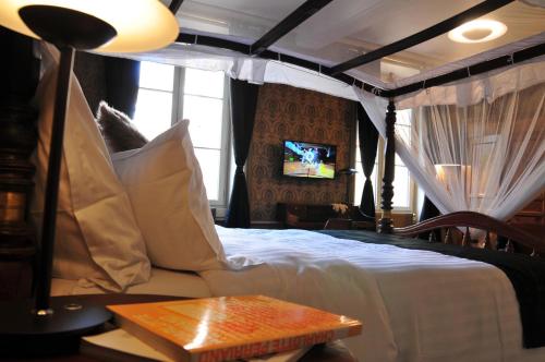 a bedroom with a bed and a tv on a wall at Les Glycines Vézelay in Vézelay
