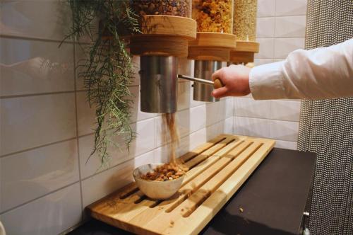 a person pouring food into a bowl on a cutting board at Trafo Hotel Baden in Baden
