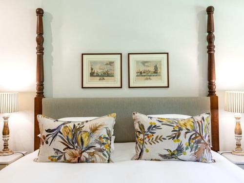 a bedroom with a bed with two pictures on the wall at Keerweder Cottages in Franschhoek