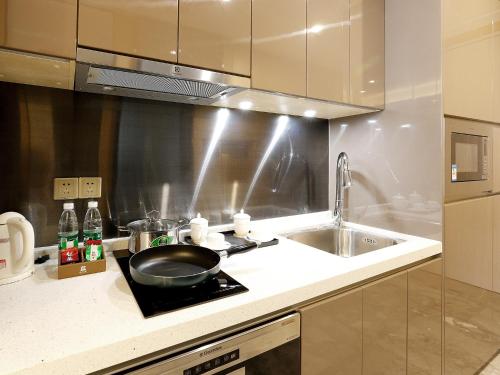 a kitchen with a sink and a frying pan on a stove at Pengman Beijing Road A-mall Apartment - Free Shuttle to Canton Fair in Guangzhou