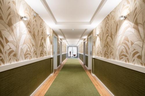 a hallway with wallpaper on the walls and a green carpet at Parkhotel Güldene Berge in Weißenfels