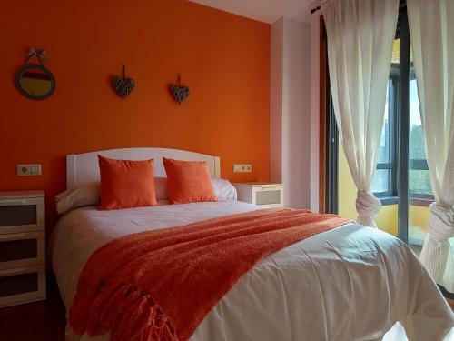 a bedroom with a bed with orange walls and a window at Apartamento luminoso y acogedor in Salvatierra de Miño