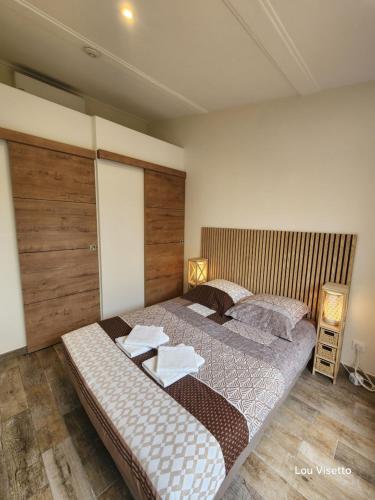 a bedroom with two beds and a wooden wall at Lou Visetto à Vallon-Pont-d'Arc in Vallon-Pont-dʼArc