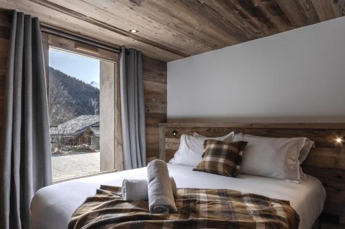 a bedroom with a bed and a large window at Ferme des Tétras - Chalet de prestige en montagne in Saint-Gervais-les-Bains