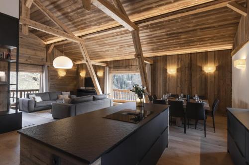 une cuisine et un salon avec des plafonds en bois et une grande île dans l'établissement Ferme des Tétras - Chalet de prestige en montagne, à Saint-Gervais-les-Bains