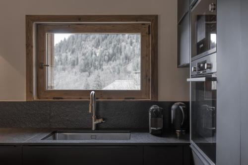 a kitchen with a sink and a window at Ferme des Tétras - Chalet de prestige en montagne in Saint-Gervais-les-Bains